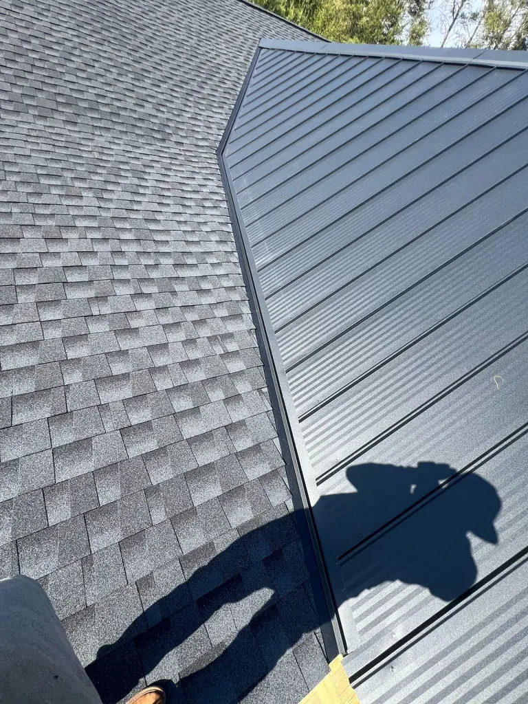 Architectural shingles meeting black standing seam metal roofing