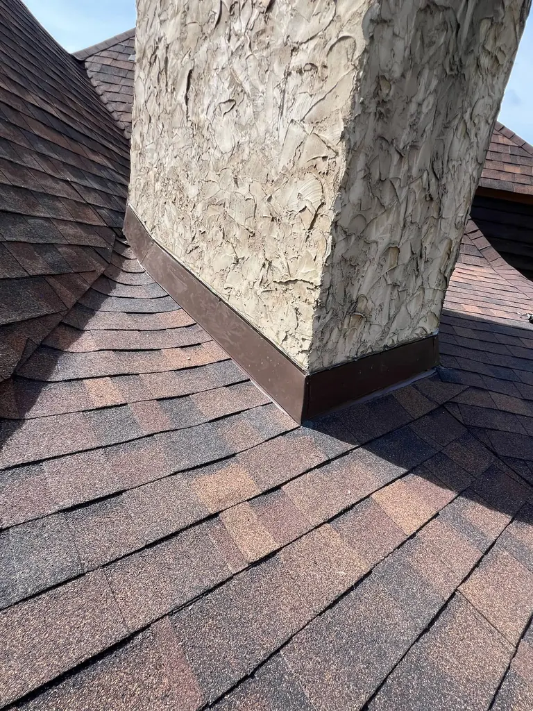 New chimney step flashing installed on a shingle roof
