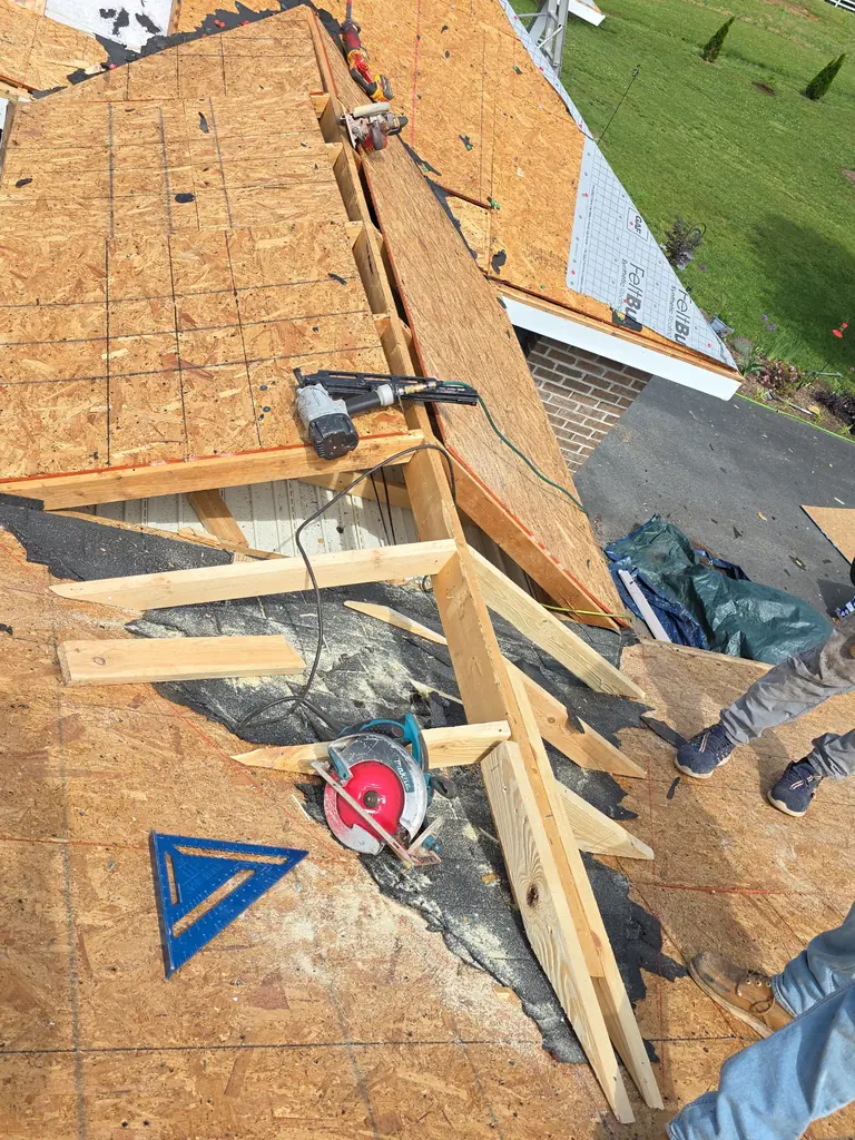 Installer removing storm-damaged shingles from a residential roof